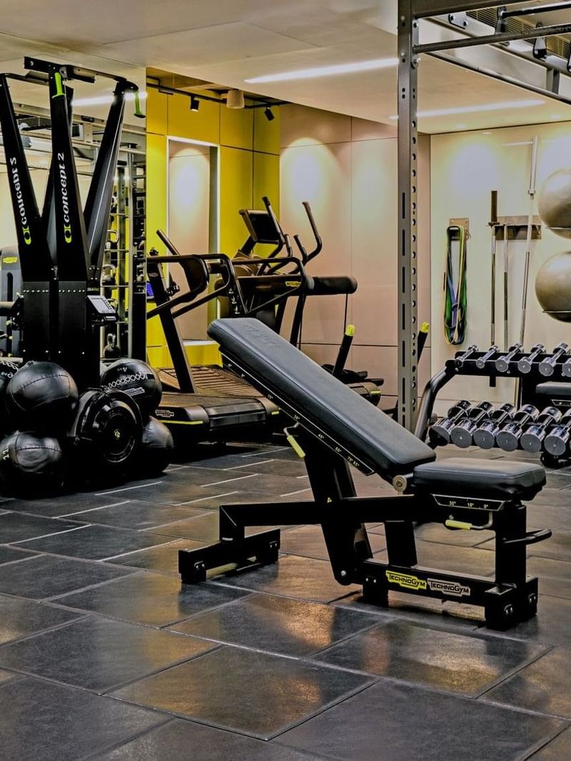 Modern gym with various equipment and black tiled floor at The May Fair Hotel.