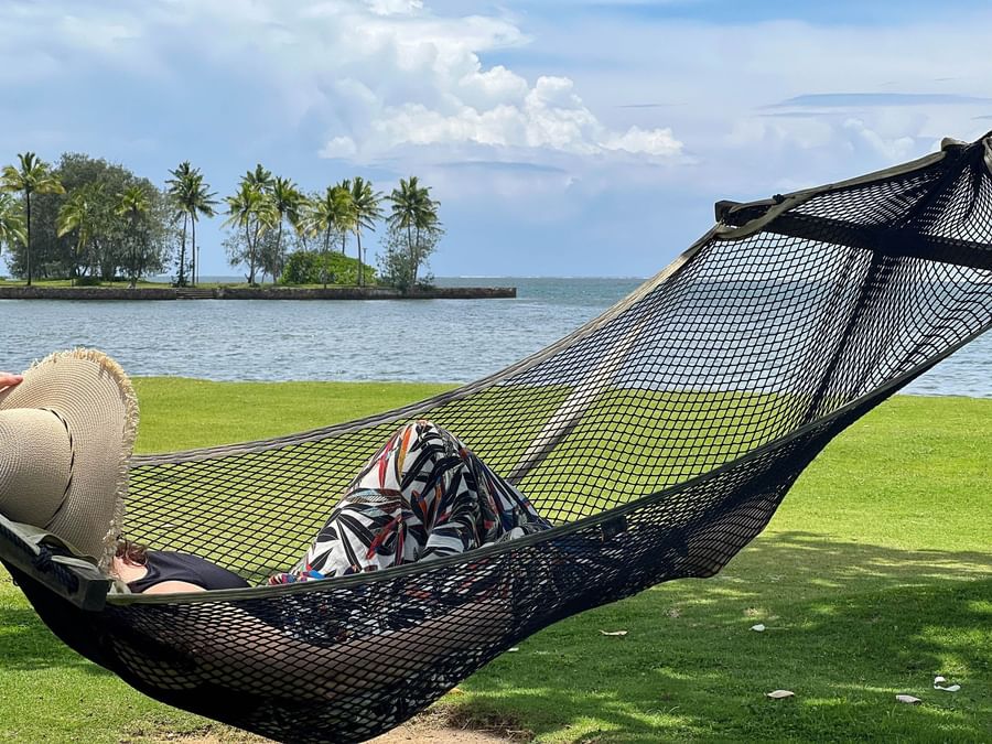 Person relaxing on a hammock by the ocean at The Naviti Resort Fiji.