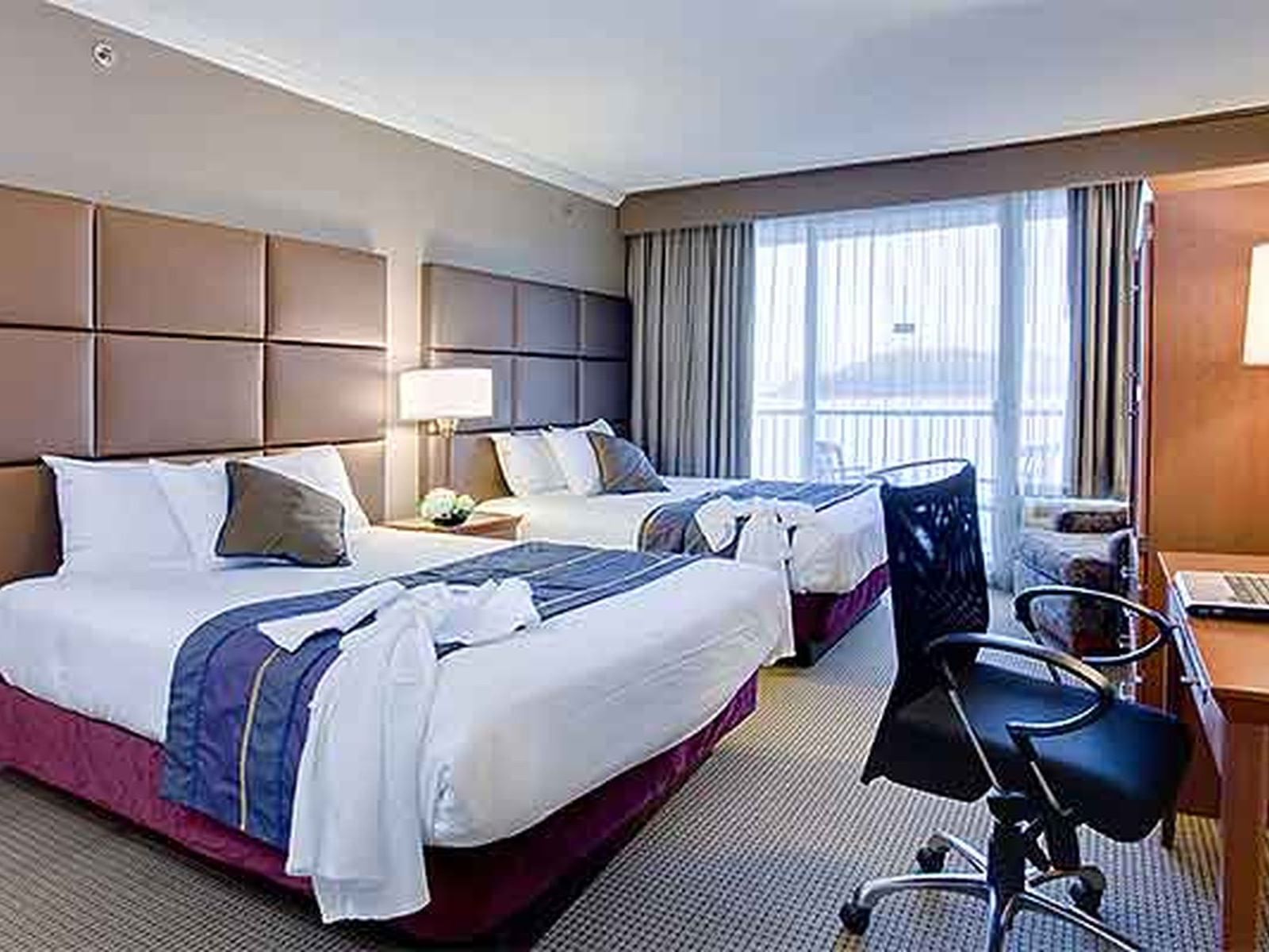 two beds in hotel room with balcony overlooking ocean