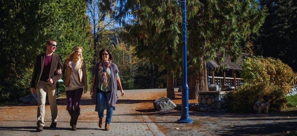 Visitors walk along a shaded path near Fitzsimmons Creek in Whistler, close to trees and park trails