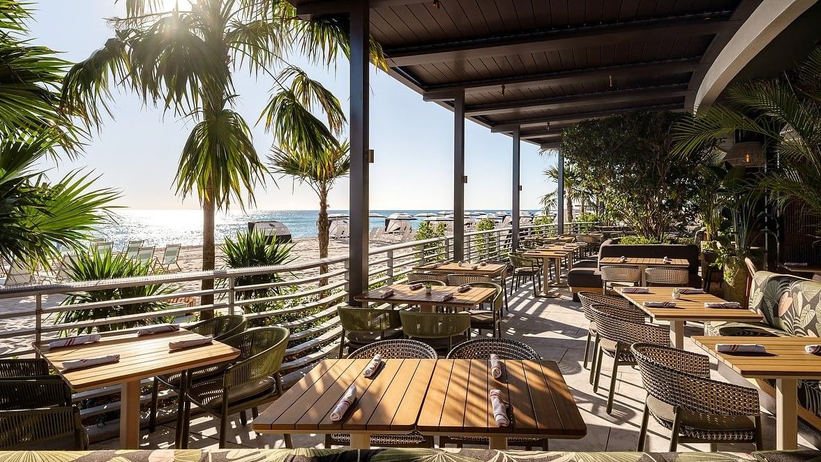 Open-air beachfront restaurant with panoramic ocean views, natural textures, and relaxed seating.
