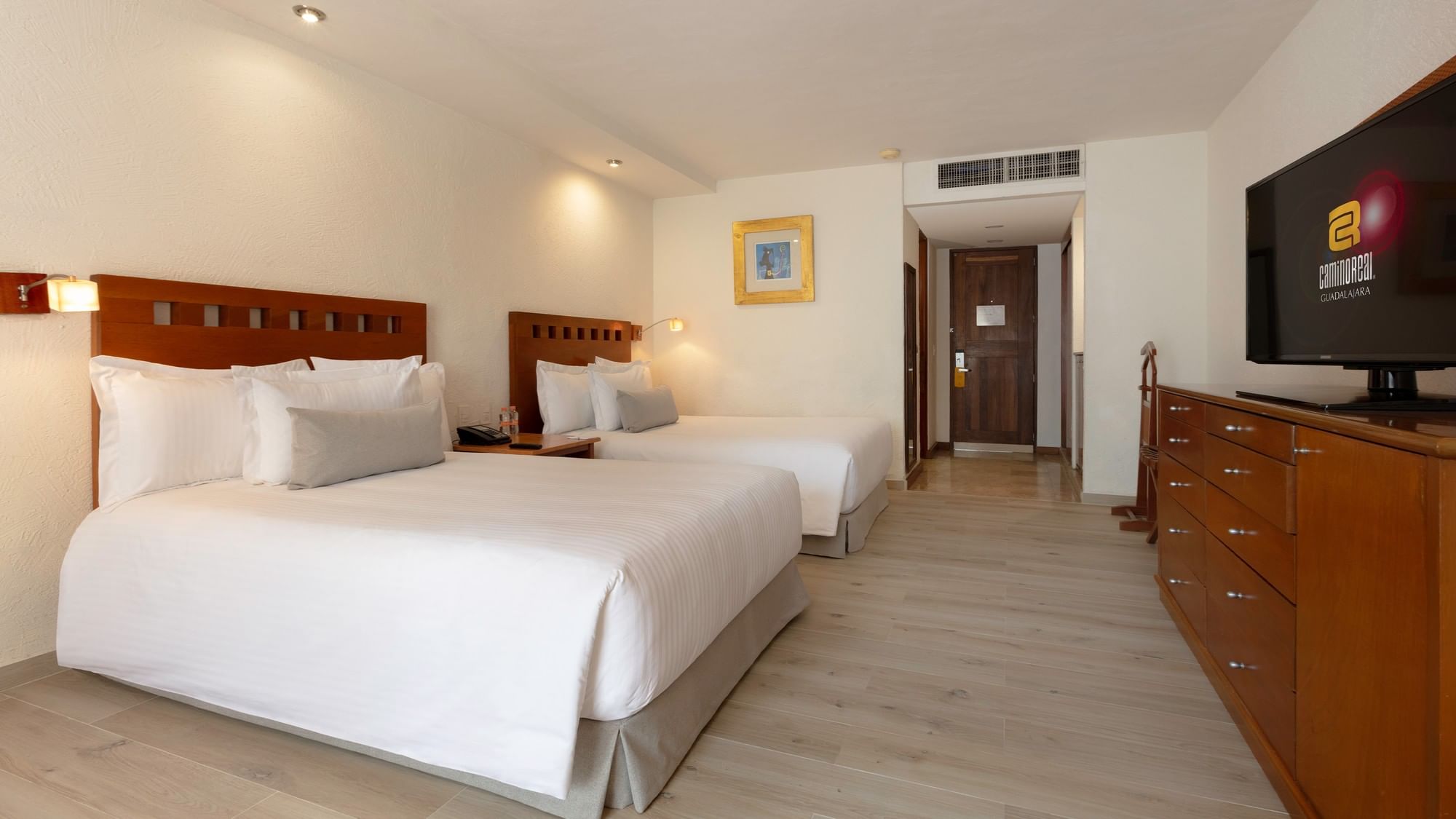 Two beds with white linens in a spacious room at Camino Real Guadalajara in Zapopan