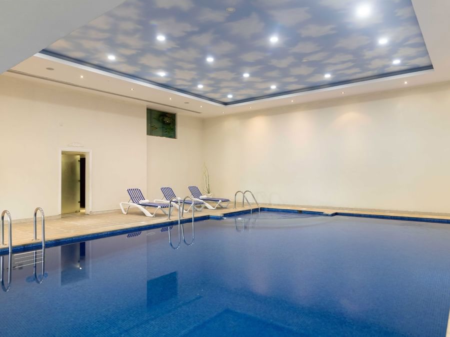 Interior of the indoor swimming pool area with lounge chairs at Warwick Al Jubail