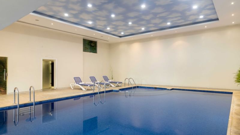 Interior of the indoor pool area with lounge chairs at Warwick Hotels and Resorts