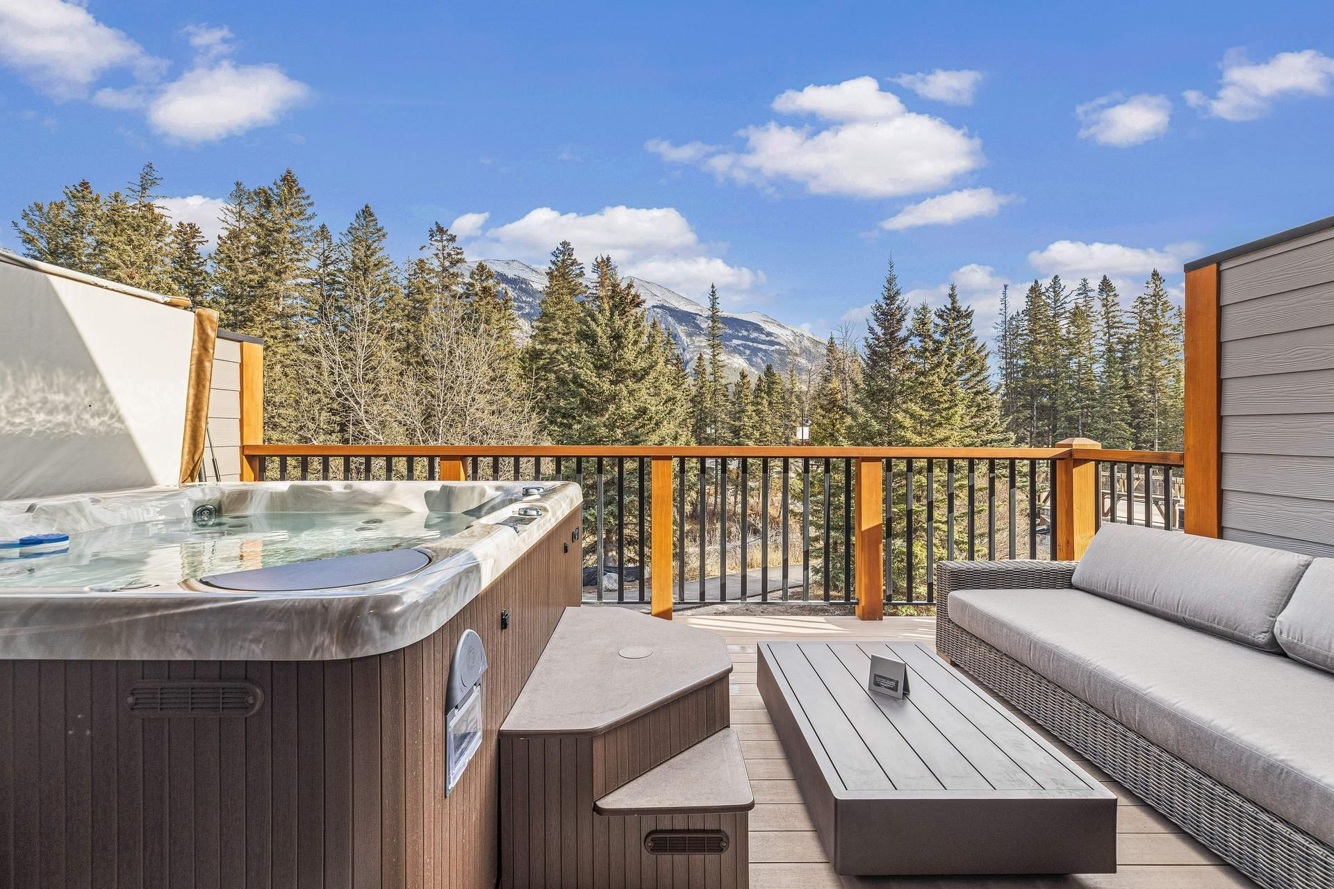 Balcony with jacuzzi and lounge furniture overlooking forested mountains at Spring Creek Vacations