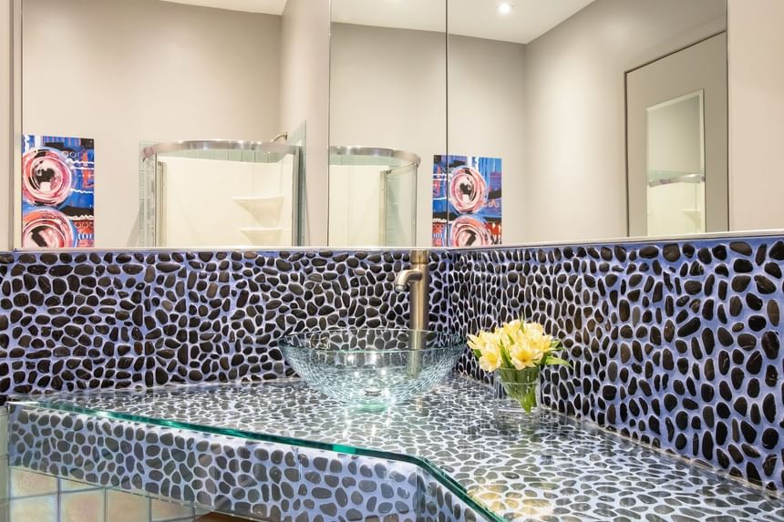 Bathroom vanity with glass washbasin, mirror & fresh flowers in Queen Premiere Blast at Retro Suites Hotel