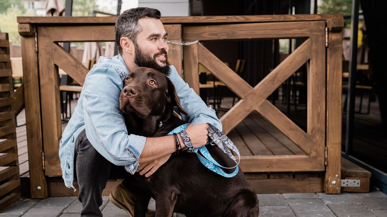 man hugging brown lab