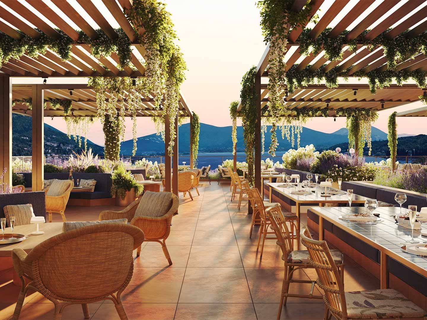 Outdoor restaurant with wooden pergolas, wicker chairs, and dining tables set against a mountain backdrop.