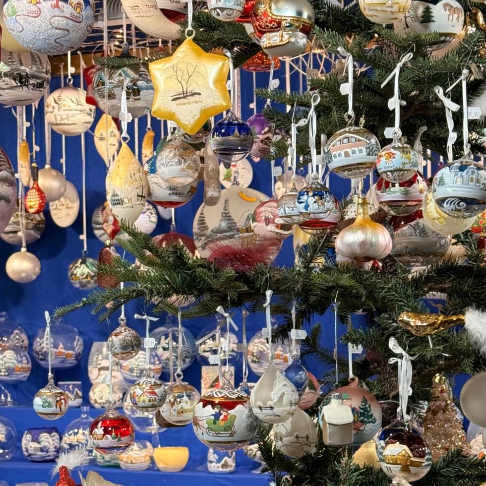 Delicate hand-painted glass ball ornaments hanging from Christmas tree branches at Falkensteiner Hotel Kronplatz