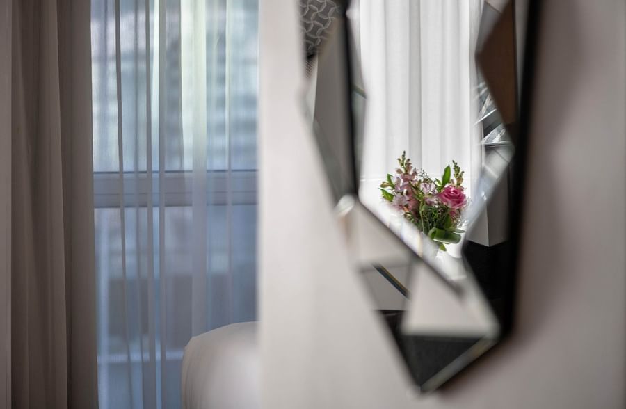 Mirror with flowers reflecting curtains in Penthouse René-Lévesque at Warwick Le Crystal Montreal