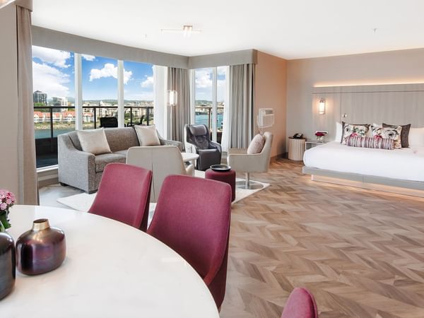 Hotel guestroom with king bed, living area, dining area, and balcony