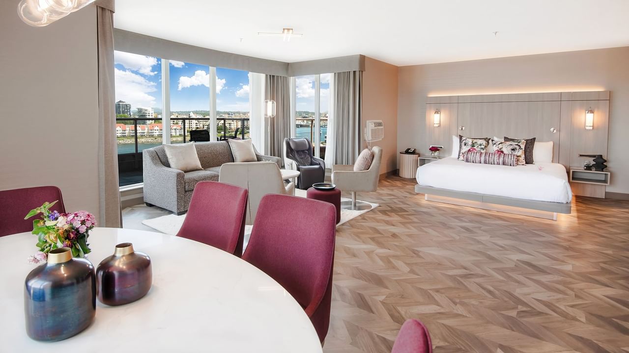Hotel guestroom with king bed, living area, dining area, and balcony