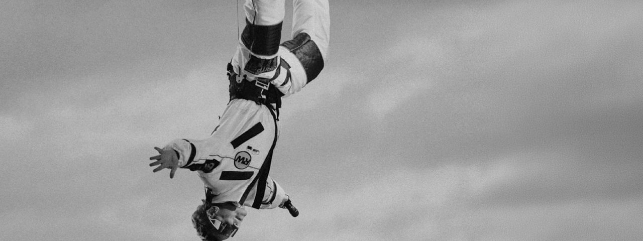 Performer upside down suspended by a line with cityscape in background for Robbie Williams – BRITPOP World Tour 2026.