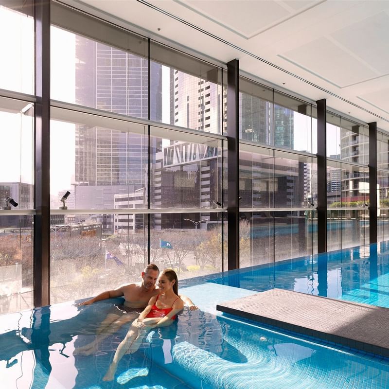 Couple relaxing on an indoor pool at Crown Promenade Melbourne