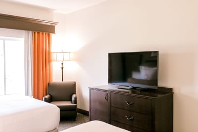 beds facing a television and window with orange curtains