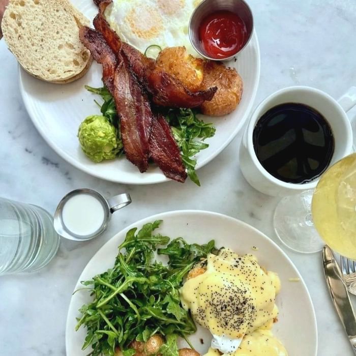 Brunch featuring fried eggs, bacon, avocado, salad, and beverages served in STELLA at Hotel Sorrento