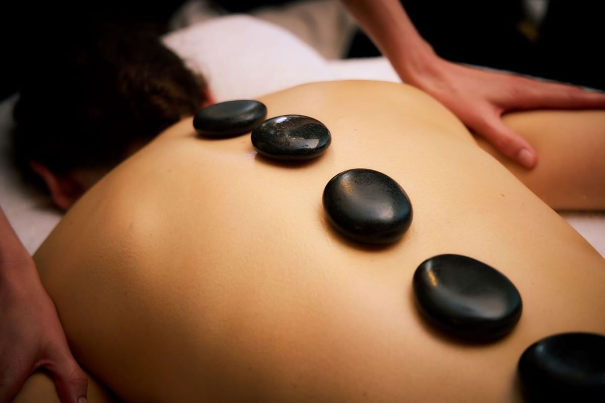 Close-up of a person receiving a relaxing hot stone massage at The May Fair Spa, The May Fair Hotel