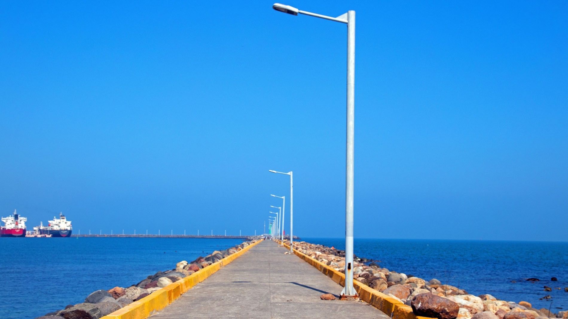 Scenic Malecón de Boca del Río with lampposts extending over the water under a clear blue sky near Camino Real Veracruz