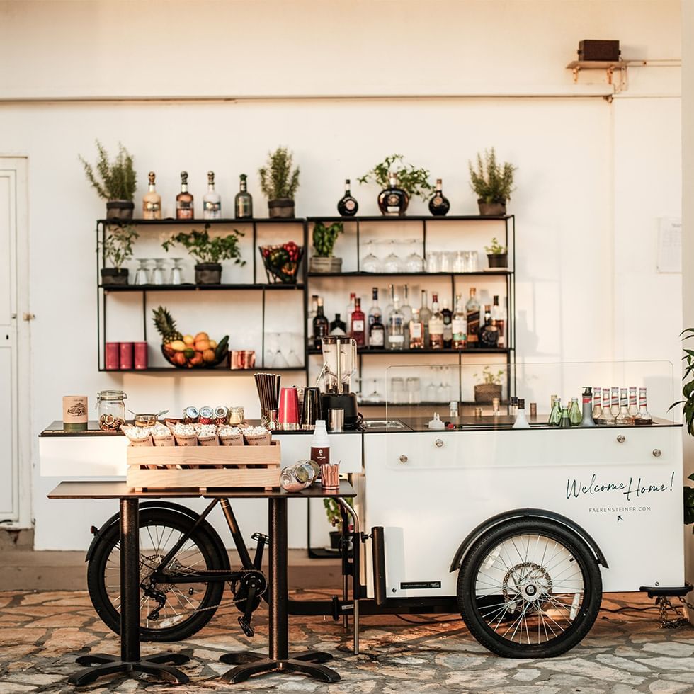 Stylish mobile bar cart with alcoholic beverages, fruits, and mixers near Falkensteiner Hotel & Spa Carinzia