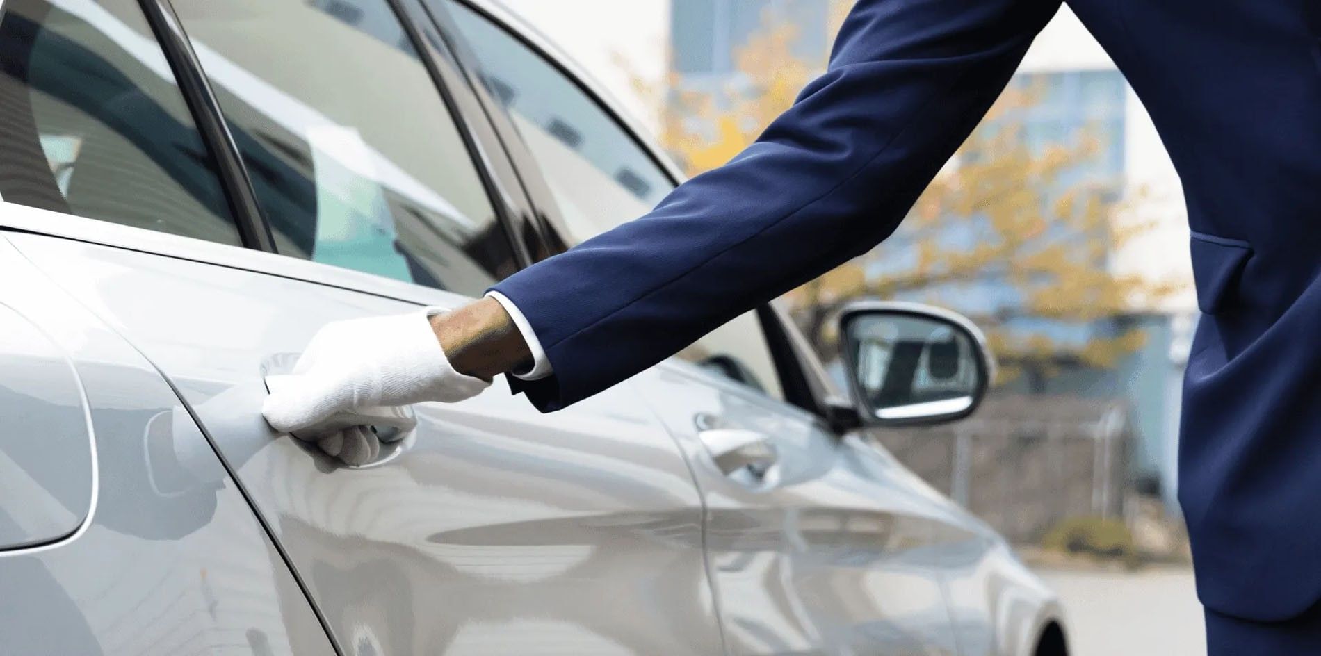 Chauffeur en costume ouvrant la portière d'une voiture de luxe à Warwick Le Crystal Montréal