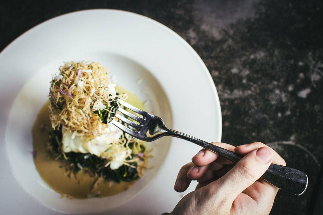 a hand holding a fork with food on it