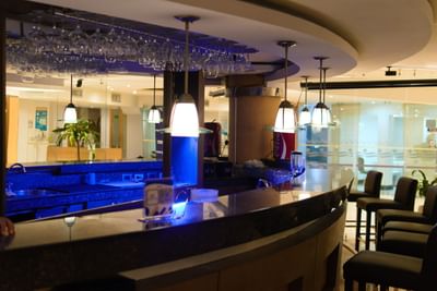 Bar iluminado de azul en el Hotel Country International, el mejor hotel de Barranquilla, donde los huéspedes disfrutan de cócteles y cenas