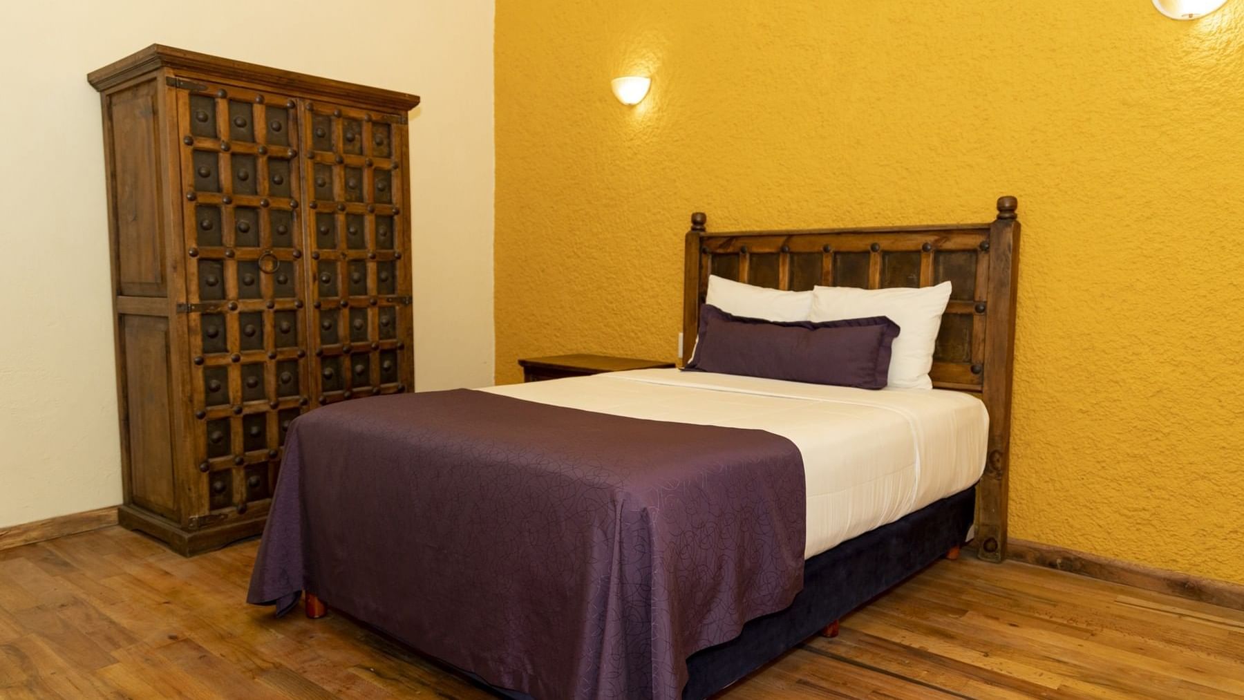 King bed, comfy pillows, wardobe closet & wooden floor in a room at Gamma Puebla Senorial Centro