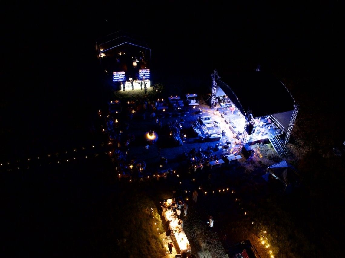 Aerial night view of La Casona illuminated with blue lighting and stage setup for an outdoor event at Royal Isabela.