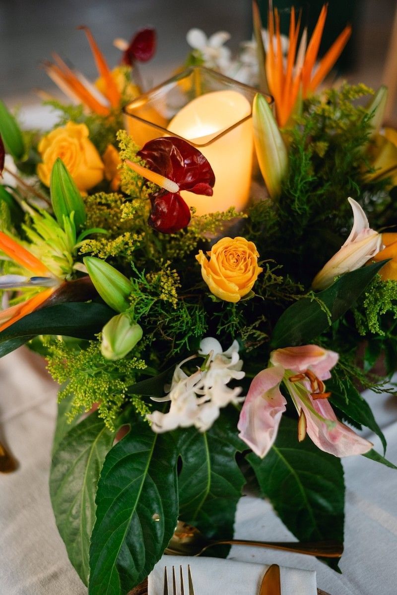 Tropical floral centerpiece with a candle in a glass vase at Morgan's Rock Reserve & Ecolodge