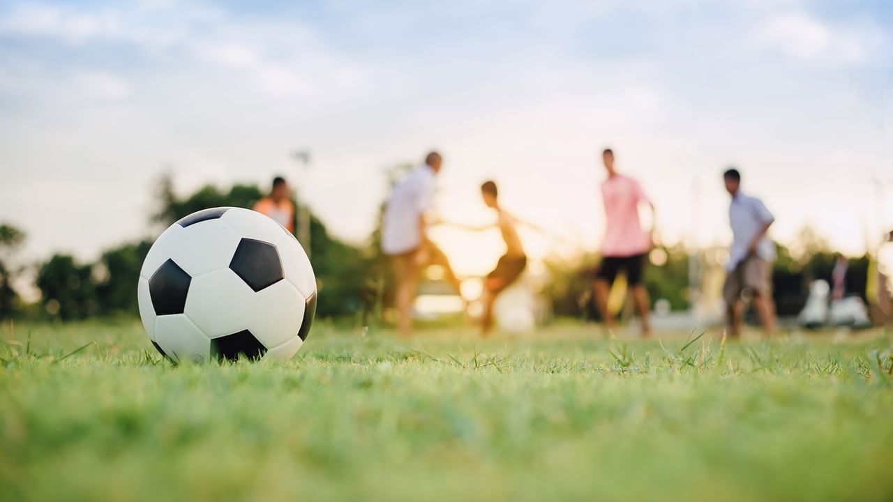 People playing soccer in Vancouver with a soccer ball in the foreground.
