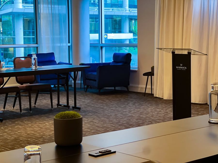 Lectern with hotel branding by blue armchairs & a table near windows in Salon Crescent 2 at Warwick Le Crystal Montreal