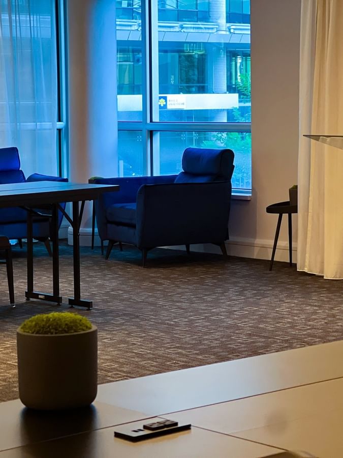 Lectern with hotel branding by blue armchairs & a table near windows in Salon Crescent 2 at Warwick Le Crystal Montreal