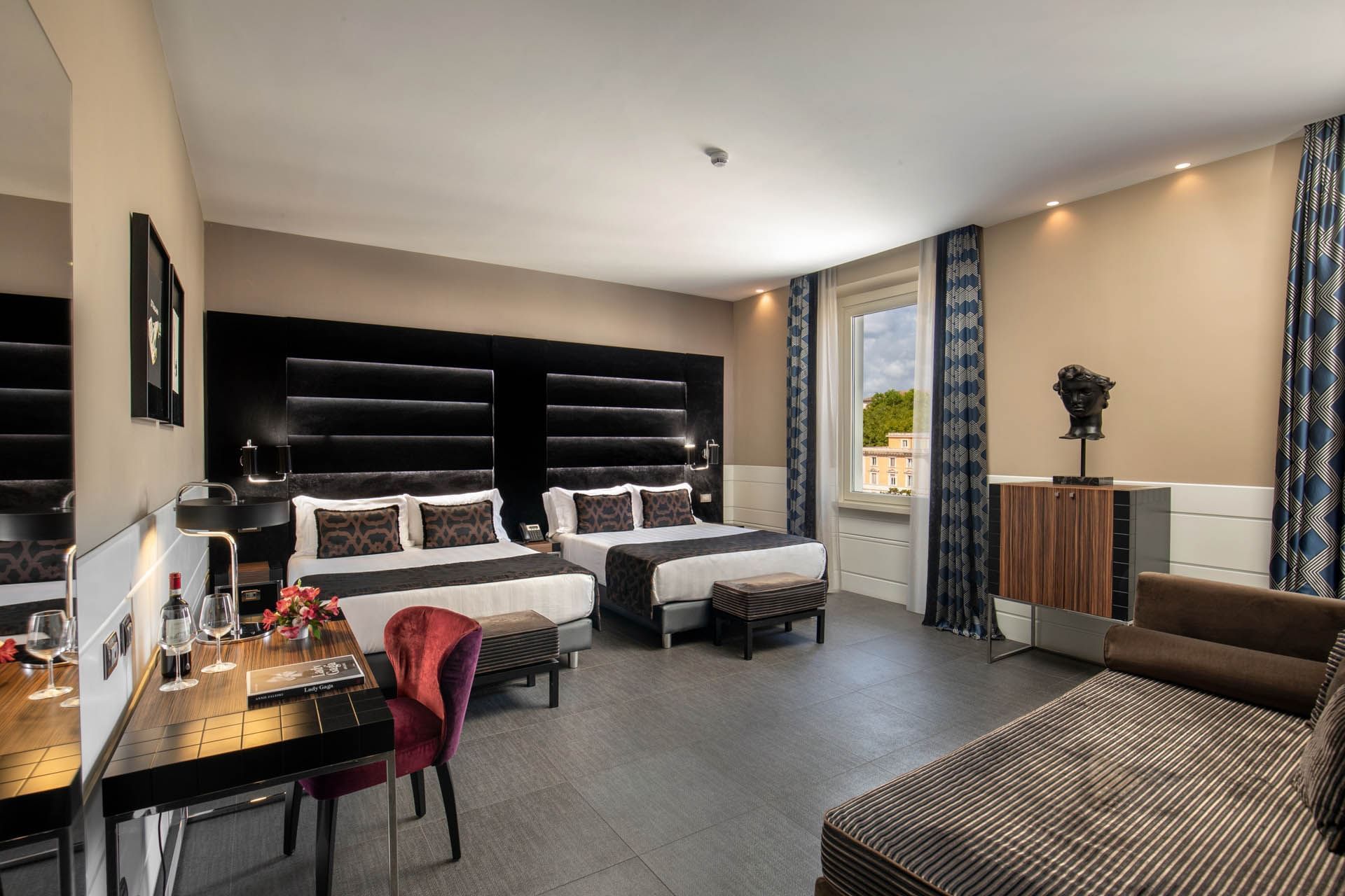 Open Suite featuring two beds by the window, a work desk, and tile flooring at The Glam Hotel