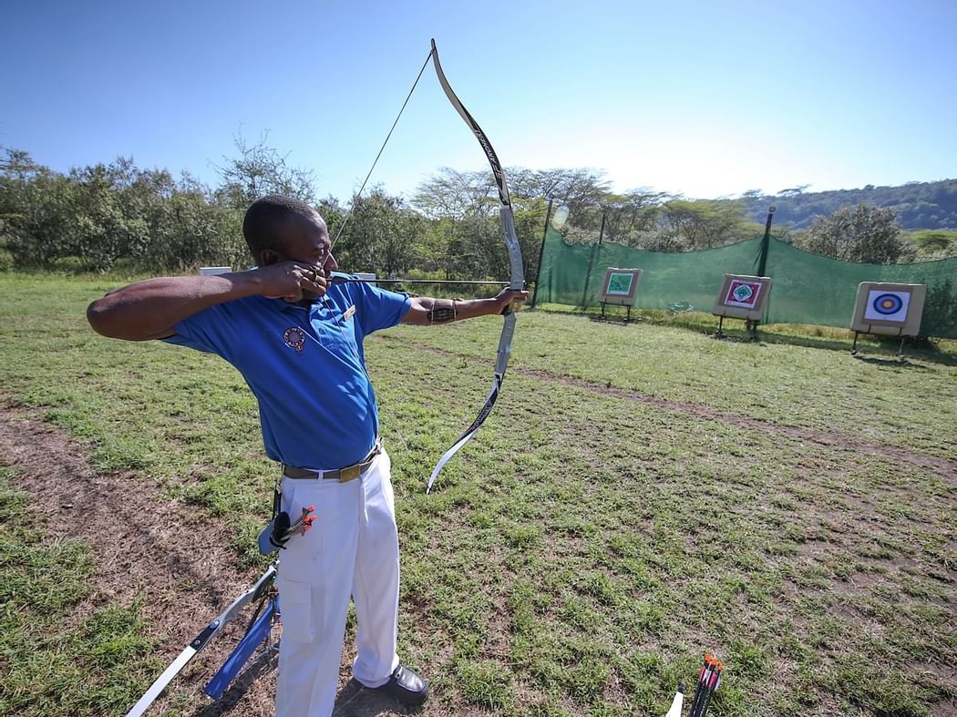 A man aiming with a bow and an arrow at Hotel Lake Elmenteita