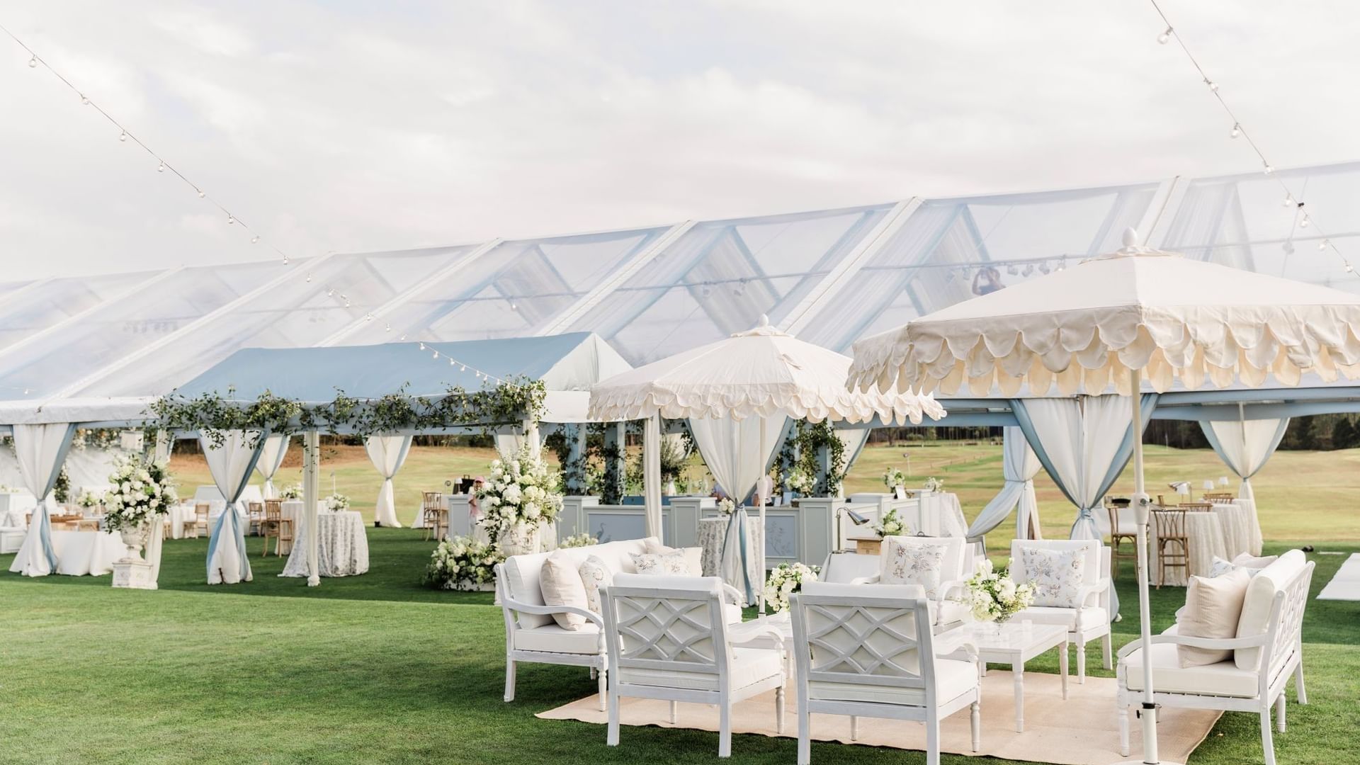 Elegant outdoor wedding setup with tents and white furniture at Camp Creek Driving Range in Inlet Beach.