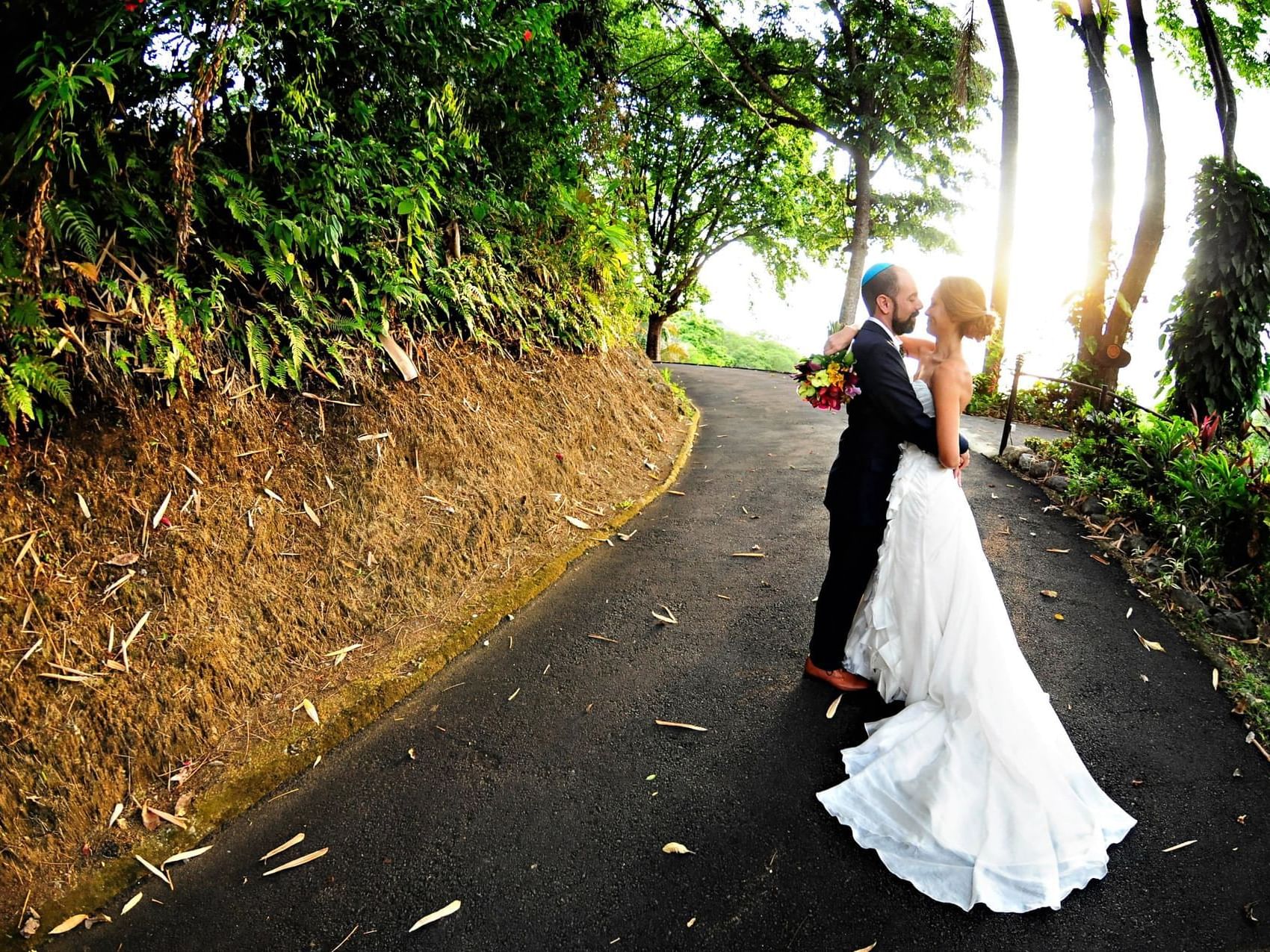 Bride and groom posing by a forest path, surrounded by lush greenery near Hotel Port Royal