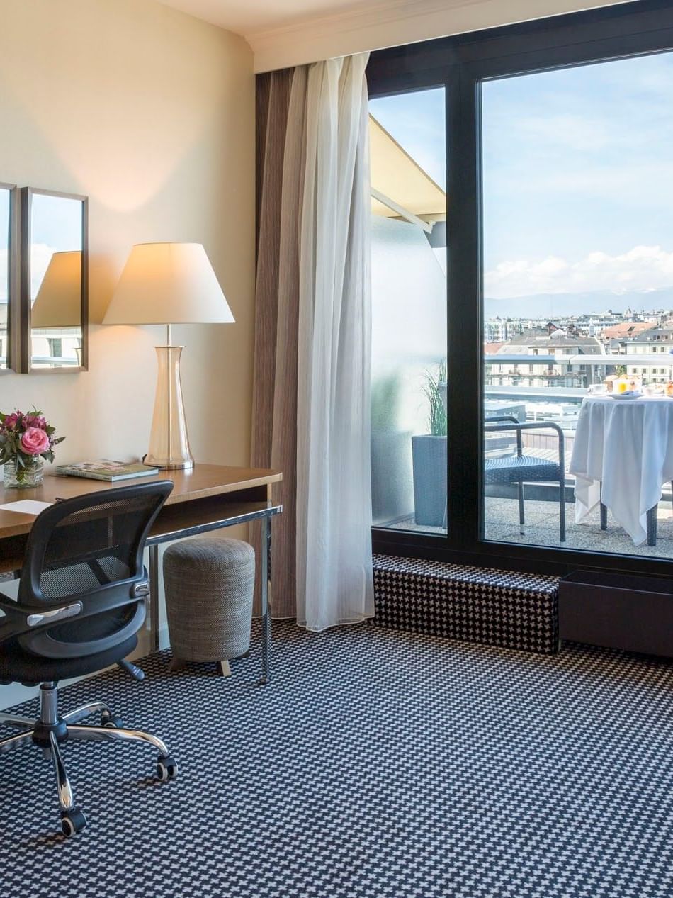 Penthouse Executive Terrace Room with Wooden desk by a black chair and mirrors, facing a balcony at Warwick Geneva