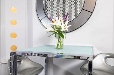 Dining table for two with a vase of fresh flowers in Queen Premiere Blast at Retro Suites Hotel