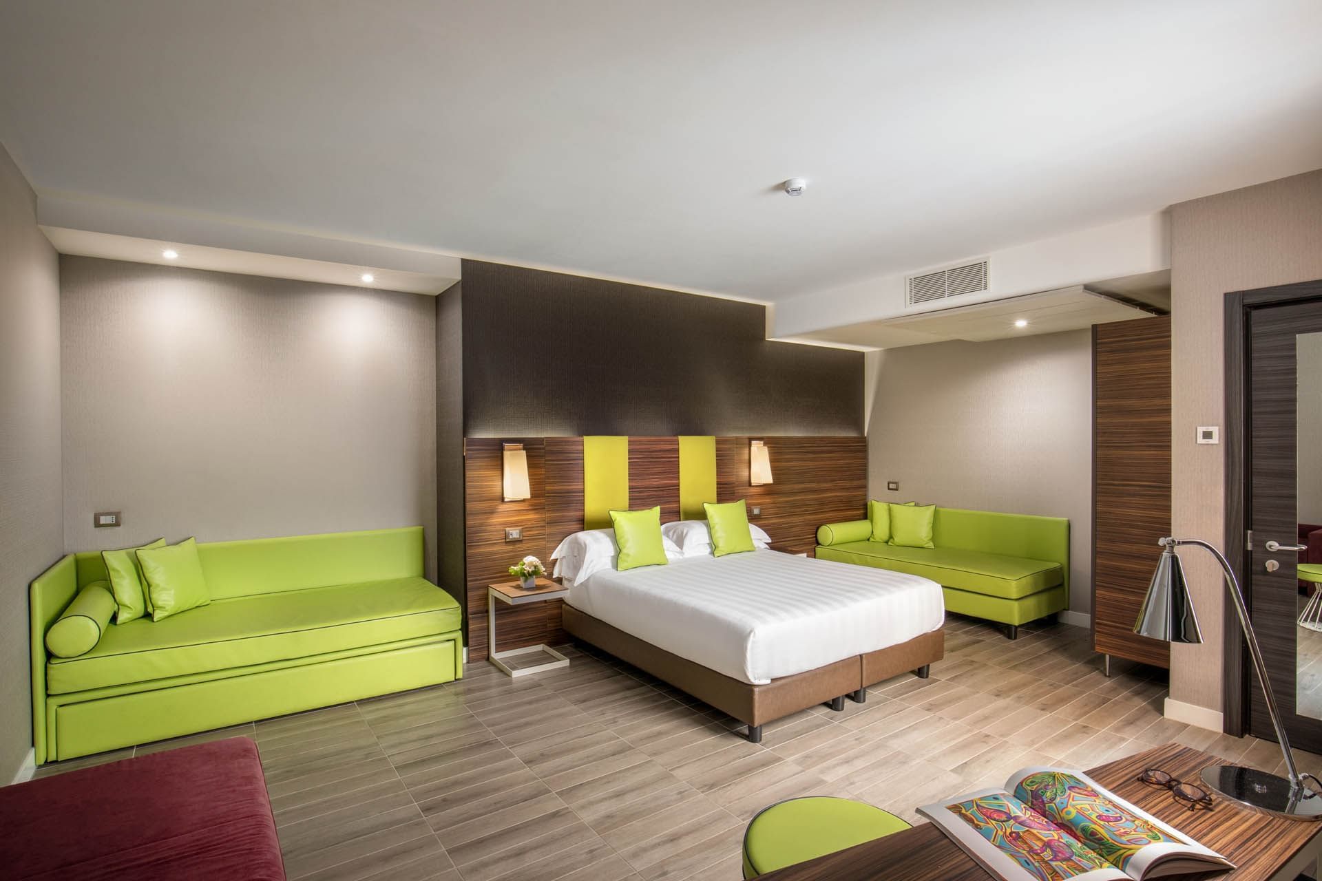 Superior Room featuring a queen bed, vibrant green accents, cozy seating area, and contemporary decor at The Republic Hotel