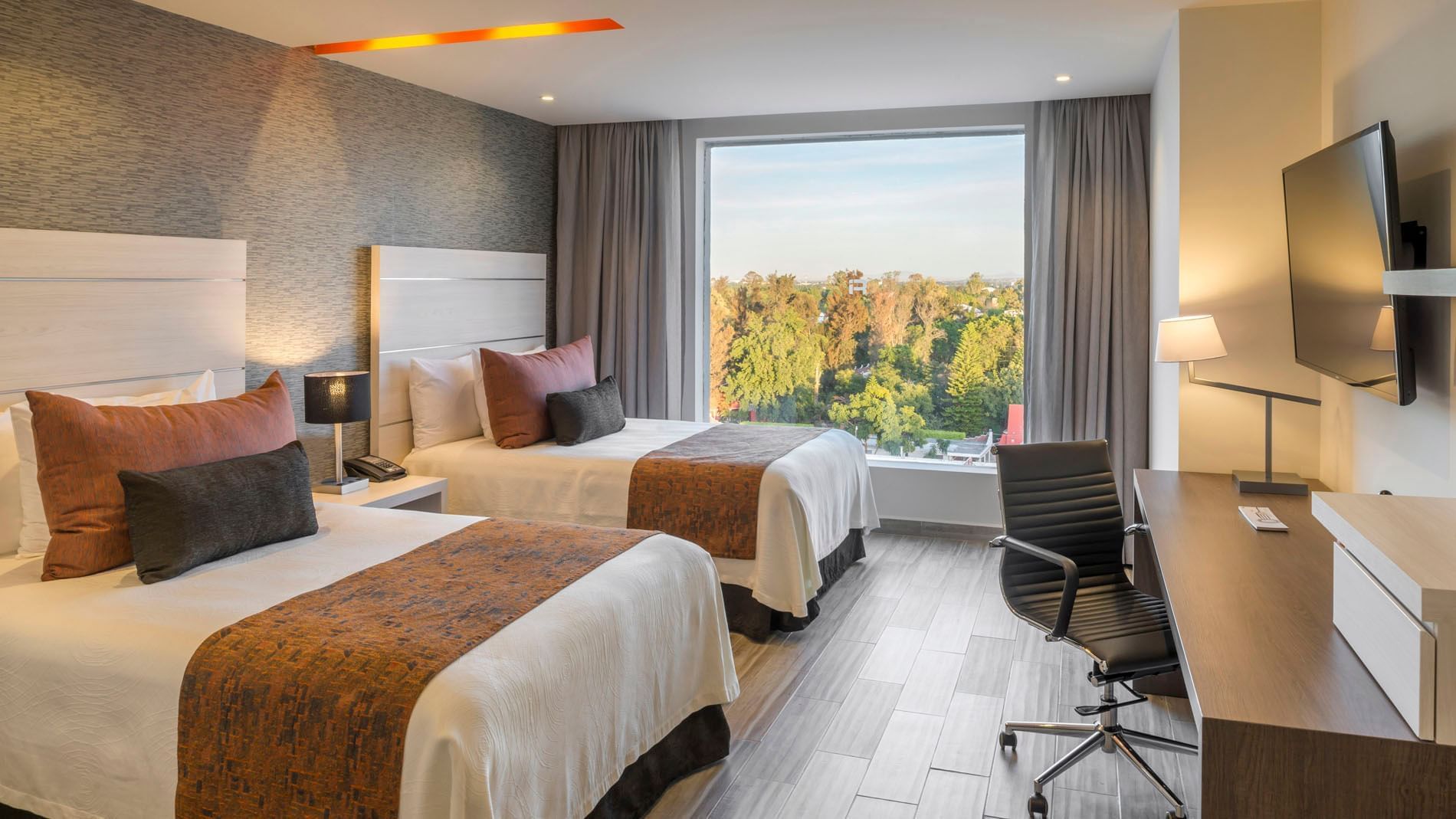 2 Double Deluxe room view showing lush green trees through a large window next to the work desk at Real Inn Celaya