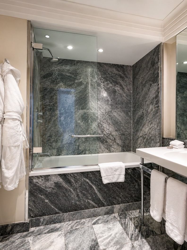 Bathroom with a bathtub, white towels, and a large mirror at The Capital Hotel, Apartments & Townhouse London.