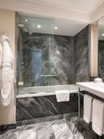 Bathroom with a bathtub, white towels, and a large mirror at The Capital Hotel, Apartments & Townhouse London.