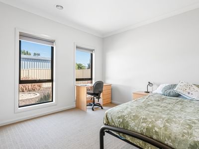 Room at La Trobe University Regional Housing with bed, desk, chair, and two windows.