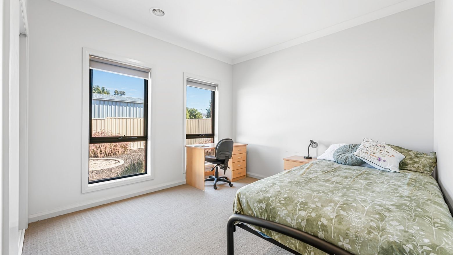 Room at La Trobe University Regional Housing with bed, desk, chair, and two windows.