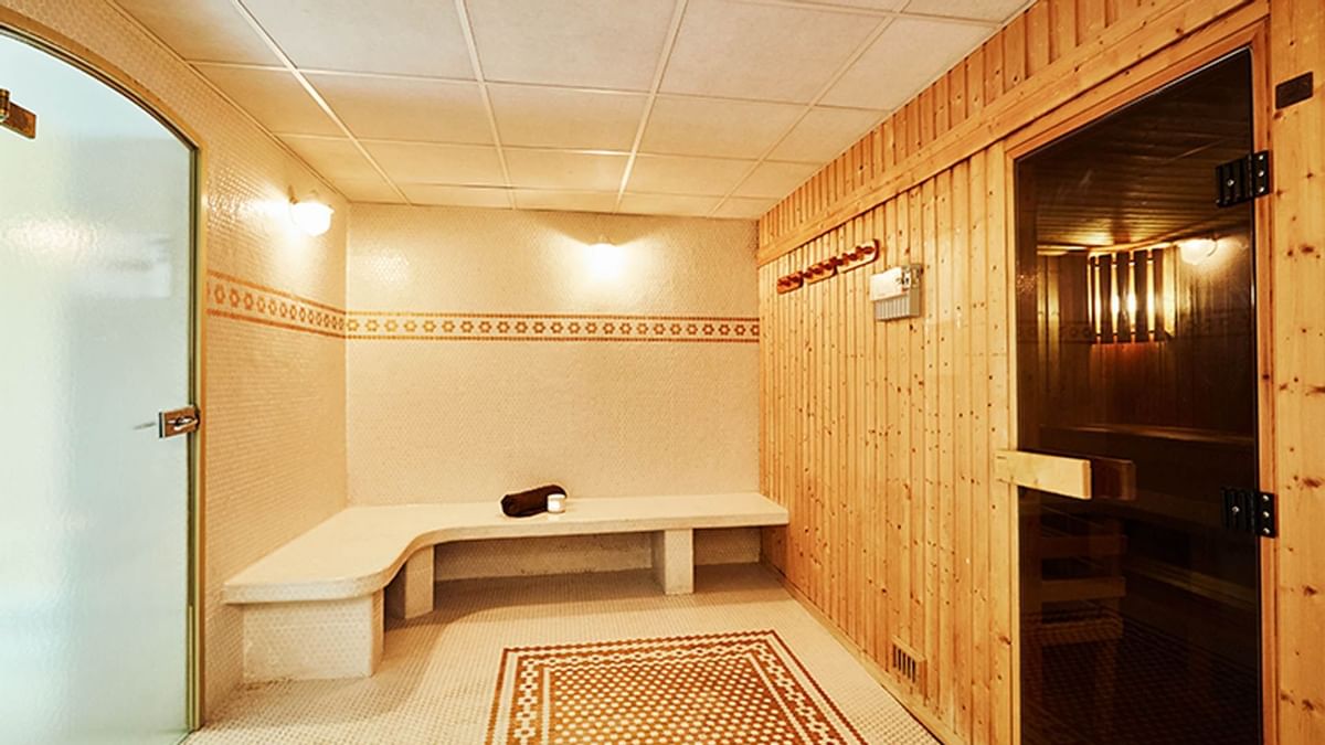 Sauna en bois avec un banc, une serviette, et une porte vitrée, parquet au sol.