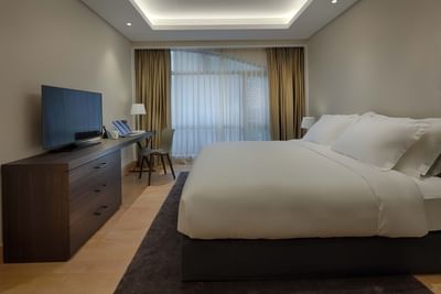 spacious guestroom with king bed, tv and work area