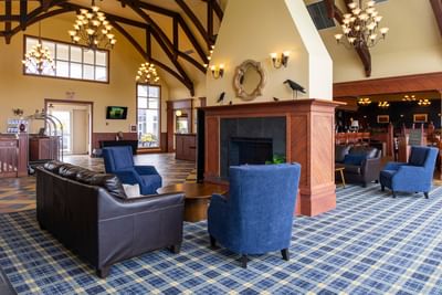 VSpacious lobby with a large wooden fireplace and blue armchairs at Rodd Crowbush Golf & Beach Resort