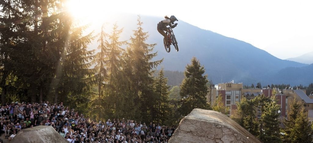 Mountain biker performs a jump above a crowd during Crankworx Whistler.