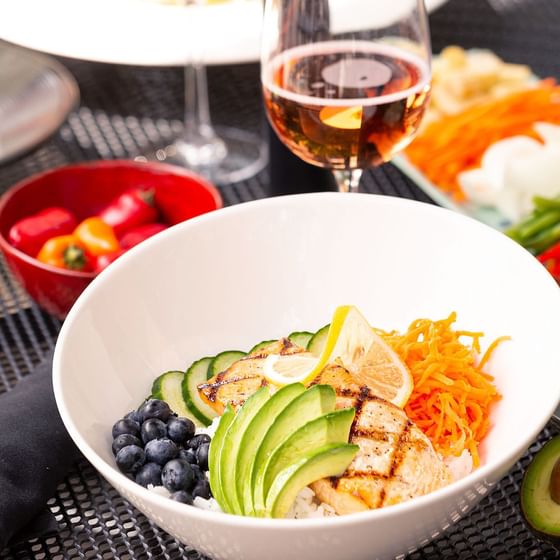 Bowl filled with a fresh salad & glass of wine at The Chilled Cork Restaurant & Lounge near Retro Suites Hotel