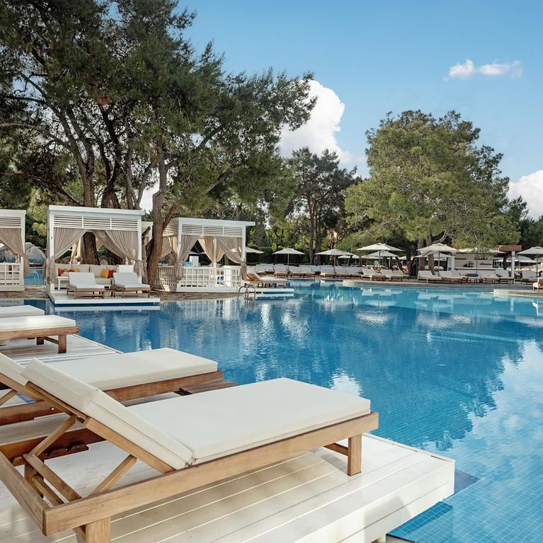 Titanic Deluxe Lara’da Olympic Havuz çevresine dizilmiş şezlonglar ve havuz kabanaları.